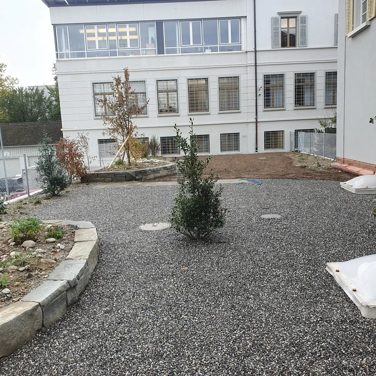Ogród żwirowy z murkiem i nasadzeniami — realizacja ze Szwajcarii